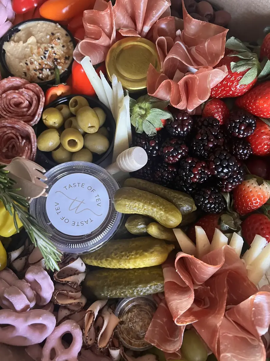 Board with prosciutto, pickles, blackberries and a branded dip cup