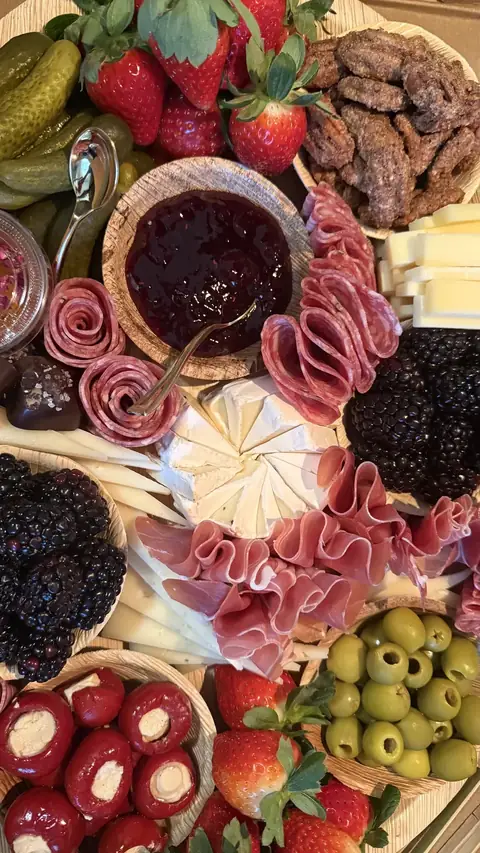 Board with brie, berries, meat roses and a bowl of honey