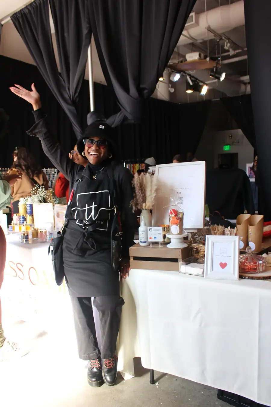 Tev standing beside a styled grazing table in a draped event space