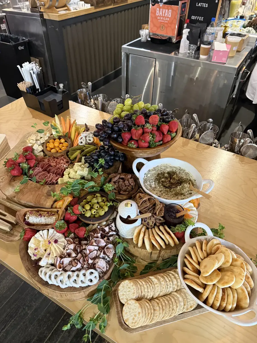 Long grazing table of fruit, cheeses and greenery running along a kitchen island