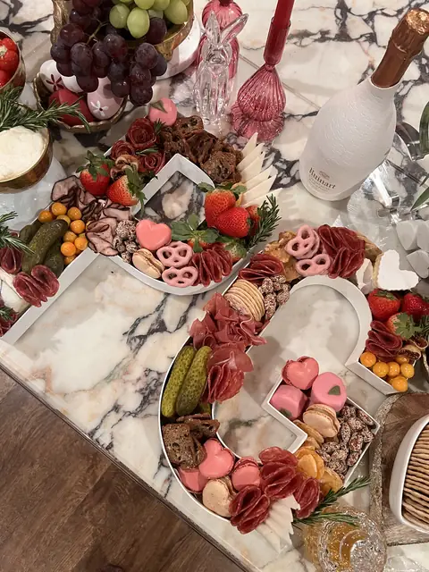Custom charcuterie letter board shaped as a T, filled with cured meats, cheeses, macarons and strawberries on marble