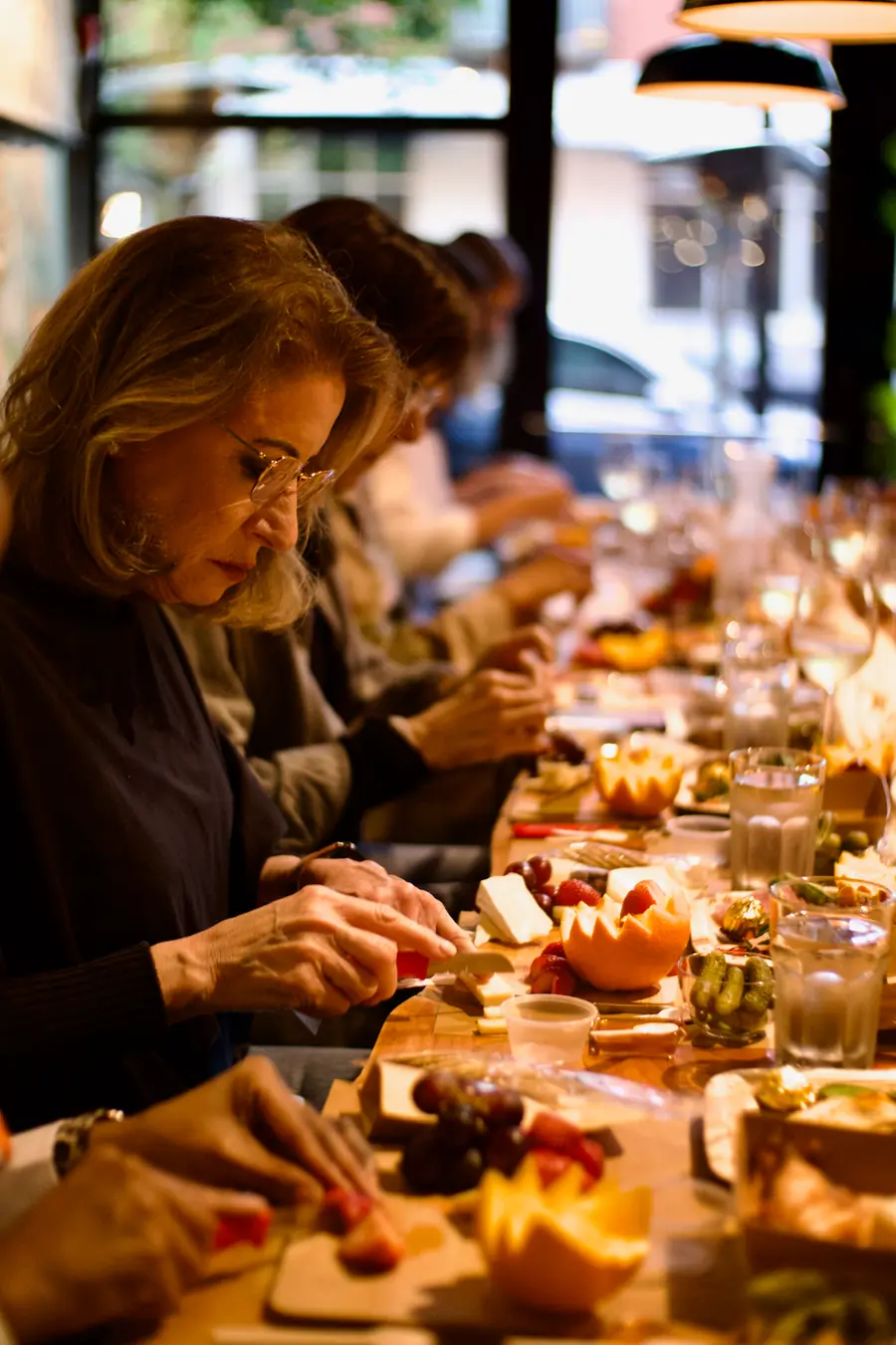 A guest arranging her own charcuterie board at a candlelit Taste of Tev workshop